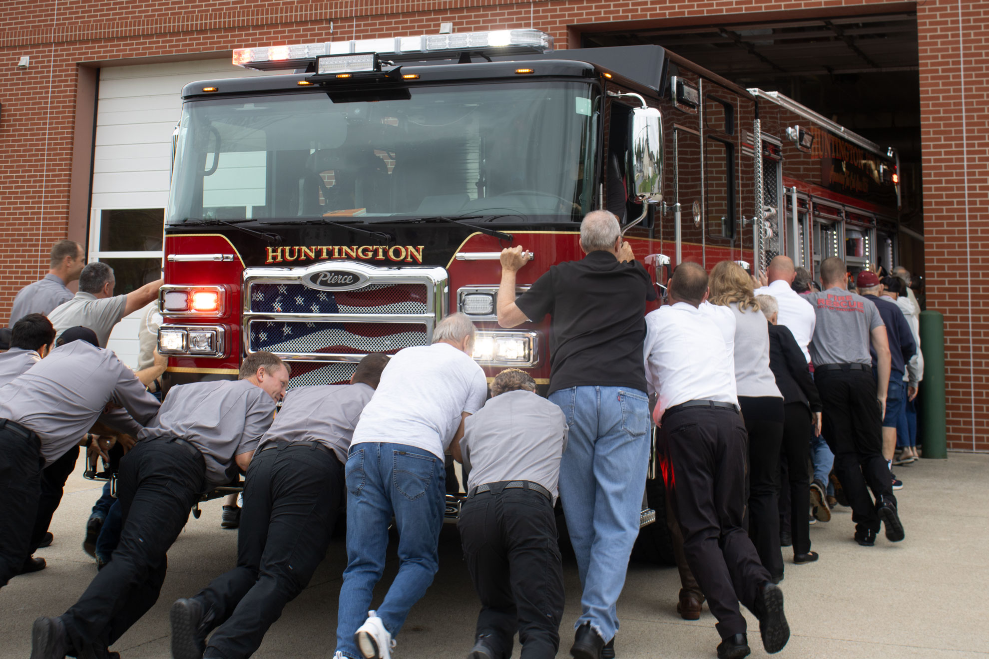 The Huntington Fire Department, city officials and others in attendance push a new fire engine into the Etna Avenue station on Monday, September 30, 2024. The 