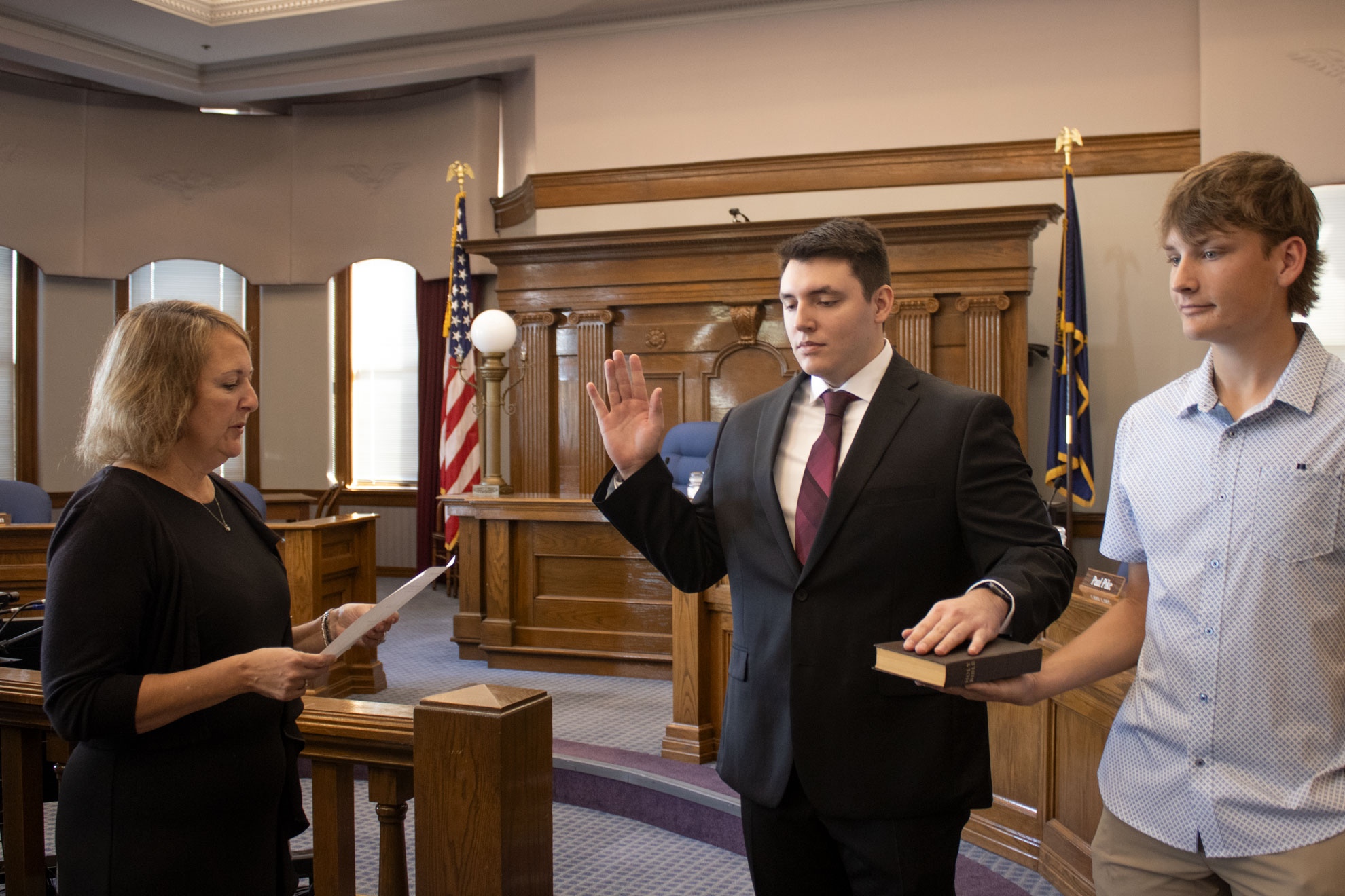 New firefighter Trae Hille takes the oath of office with his brother, Grant Drummond, holding the Bible.