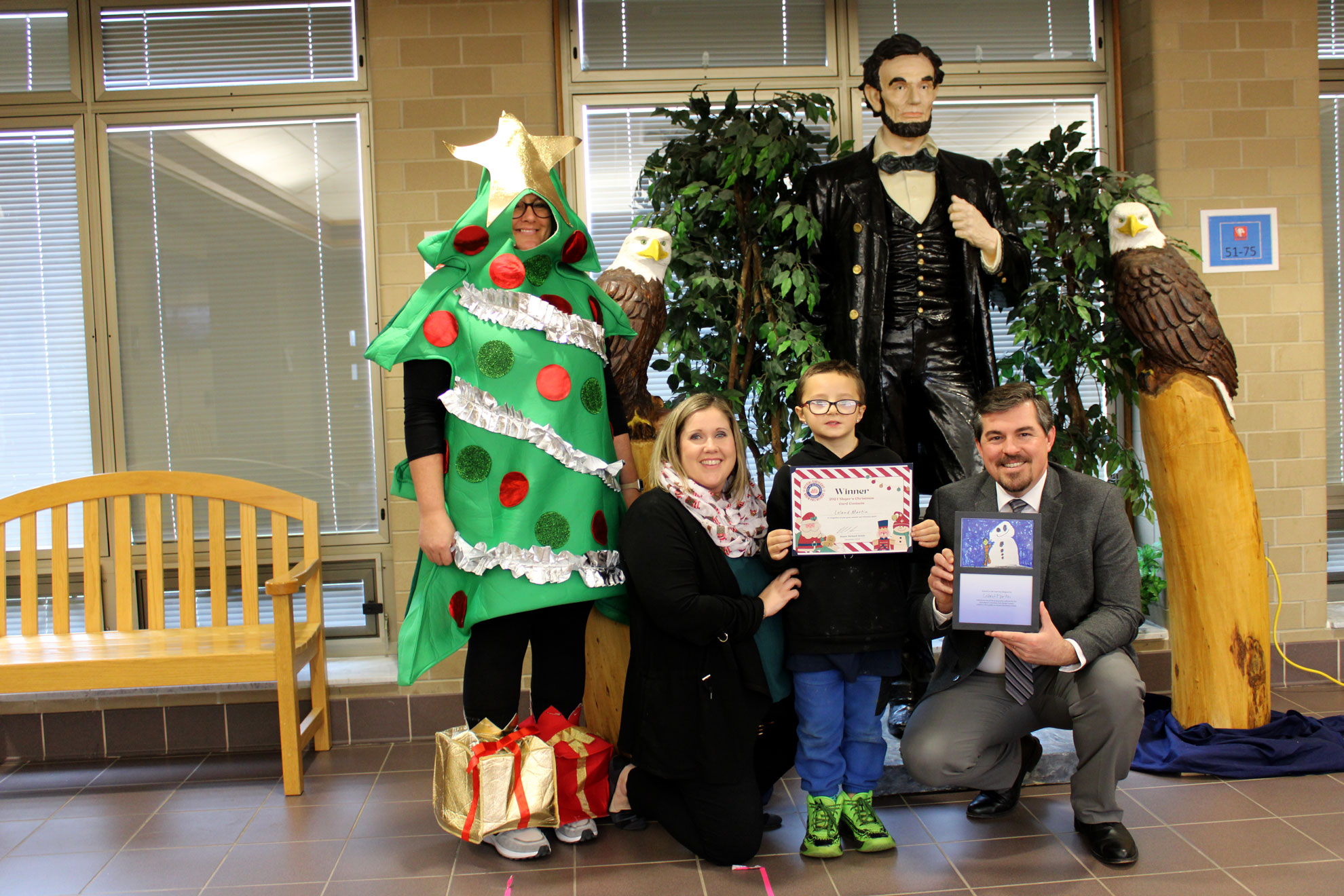 A student displays his Christmas Card art and prize