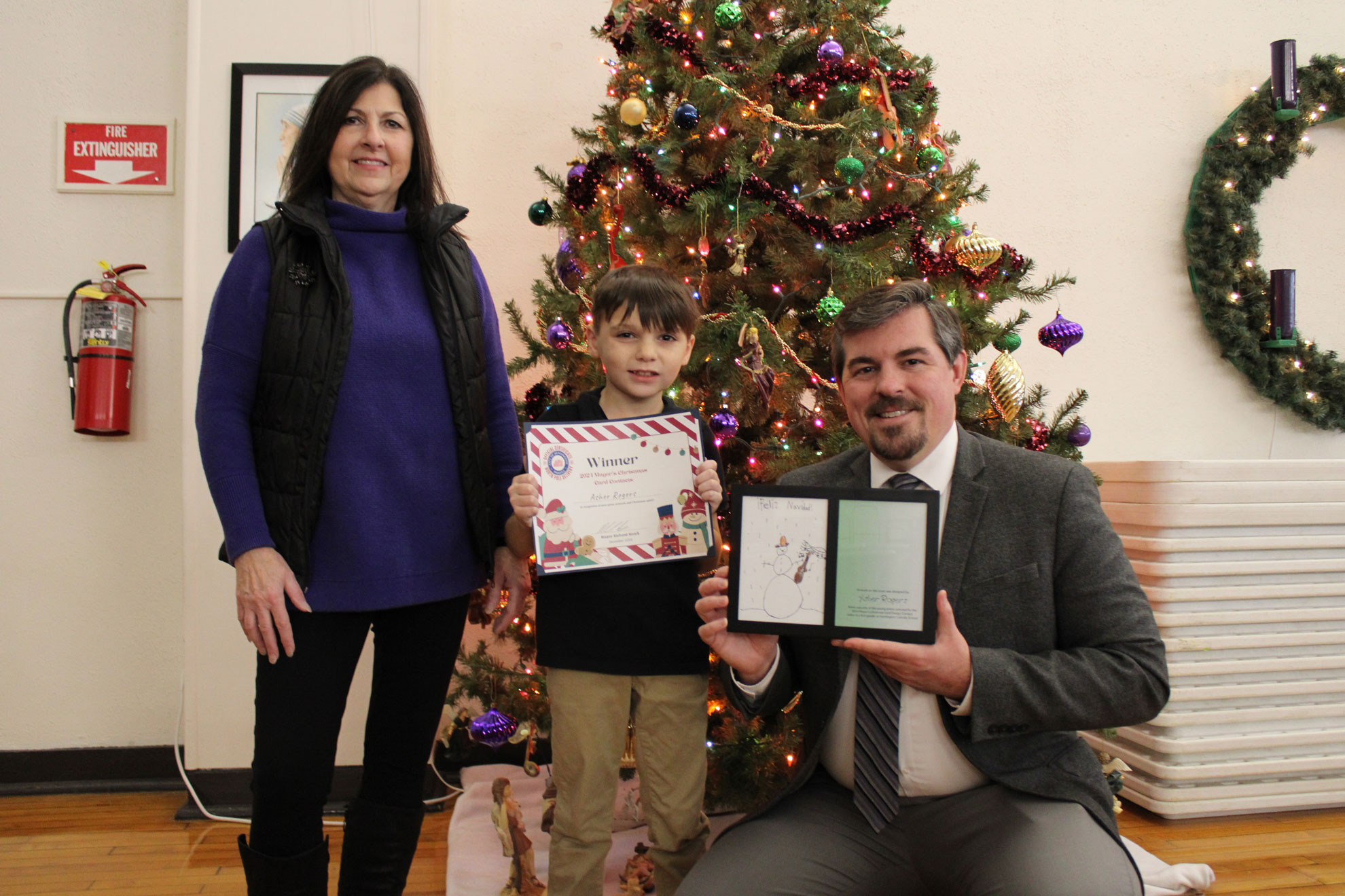 A student displays his Christmas Card art and prize