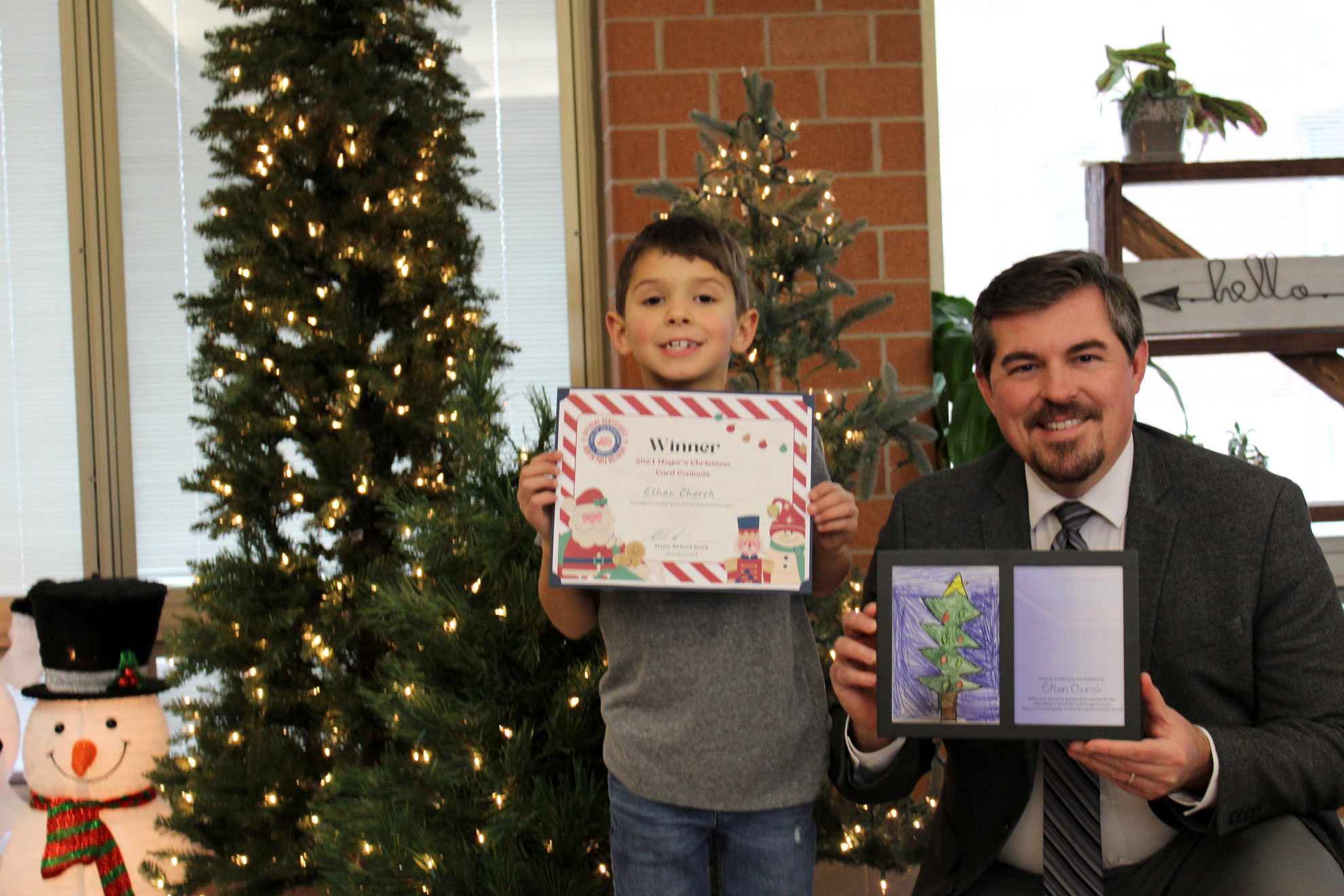 A student displays his Christmas Card art and prize