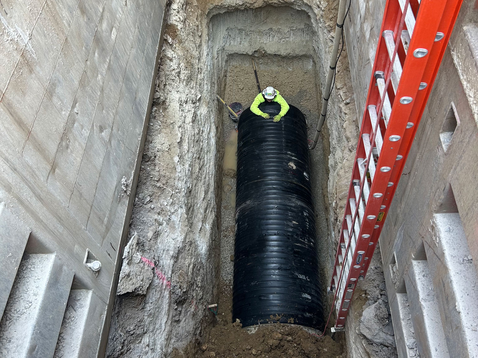 A construction worker is seen working in a 34-foot-deep trench to install a new sewer interceptor.